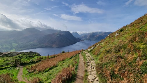 View from the Gowbarrow trail on an autumn day with path winding its way down from the fell and Ullswater stretching through the valley below.